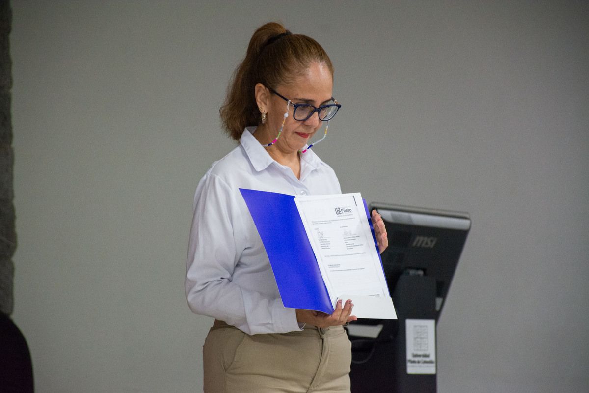 una fotografía que muestra a alejandra maría amórtegui sosteniendo el documento del convenio, firmado.