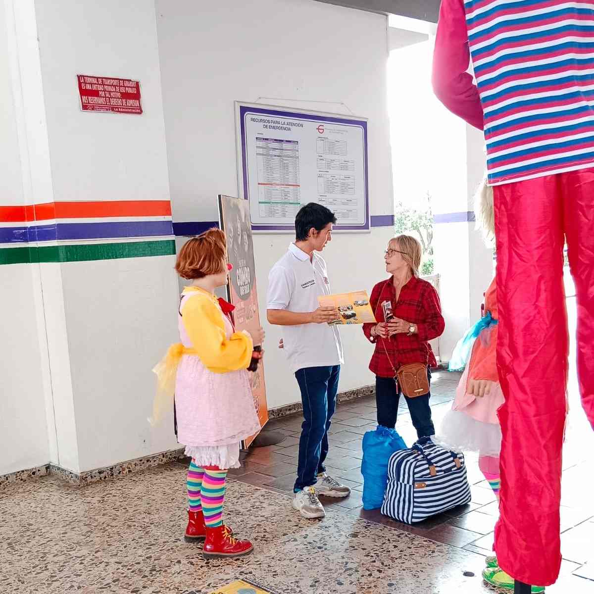 Una foto que muestra a un estudiante brindando asesoría a un turista en el terminal de transporte de Girardot.