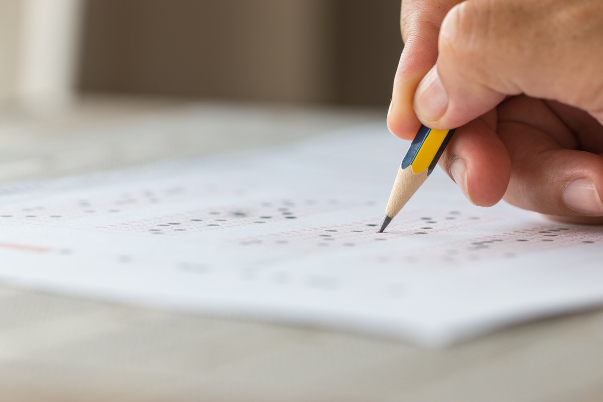 Una fotografía de una mano sosteniendo un lápiz mientras resuelte un cuestionario que parce ser de las Pruebas Saber Pro.