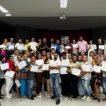 Una fotografía que muestra El grupo de actores sociales certificados gracias al curso en Gestión de Riesgo, impartido por la Universidad Piloto. En la foto se observan docenas de personas, posando con un certificado en la mano, todos muy sonrientes.