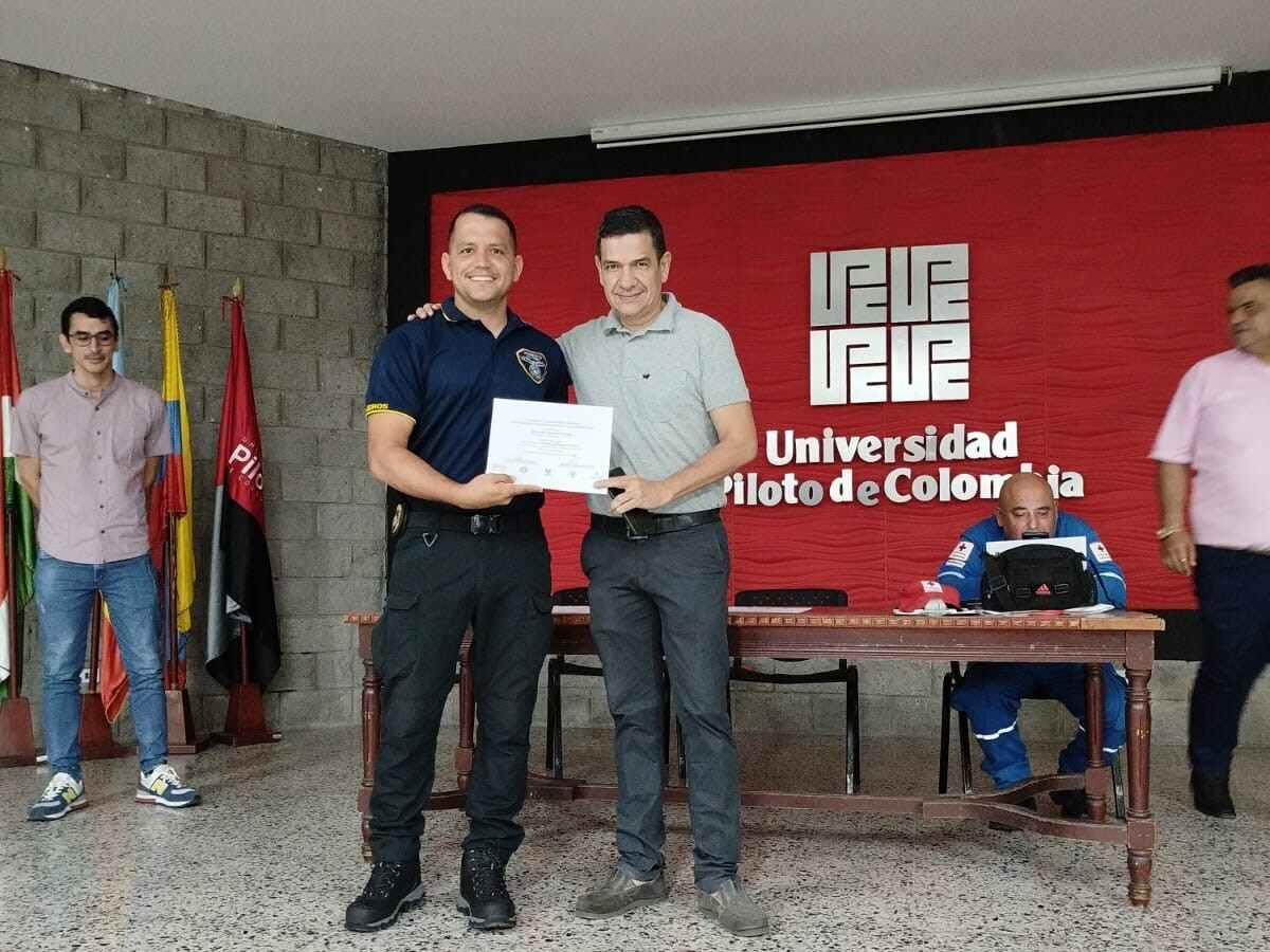 Una fotografía del docente Alexander Romero Buitrago, con camiseta gris, entregando un certificado del Curso en Gestión del Riesgo de desastres a un participante del proyecto.