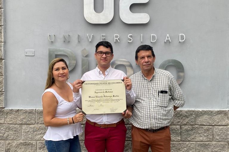 Fotografía de Manuel Patarroyo en el día de su graduación en la Universidad Piloto de Colombia. Está sosteniendo su diploma de grado junto a sus padres.