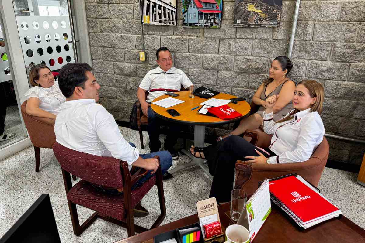 Una foto que muestra al equipo de la Universidad Piloto de Colombia en una mesa junto al alcalde y el concejal de Mesitas del Colegio, Diego Andrés López Suárez y Andrés Fernández. En la foto se observan unos documentos sobre la mesa y se percibe que todos conversan muy amenamente.