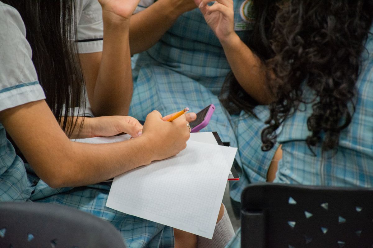 Una foto que muestra a unas estudiantes escribiendo en una hoja, están trabajando en su propuesta de innovación para el evento ‘Retos de Ingeniería 2024’ llevado a cabo en la Universidad Piloto de Colombia, Seccional Alto Magdalena.