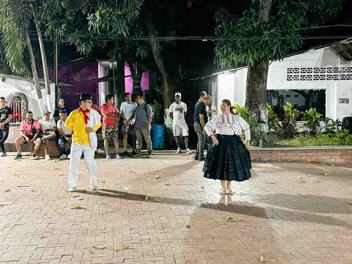 Una foto de dos estudiantes danzando en la zona libre de las instalaciones Coreducación en Honda, Tolima. Se observa un público que observa la muestra artística.