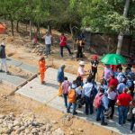 Grupo de personas posando junto a una obra de pavimentación durante la visita técnica.