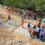 Grupo de personas posando junto a una obra de pavimentación durante la visita técnica.