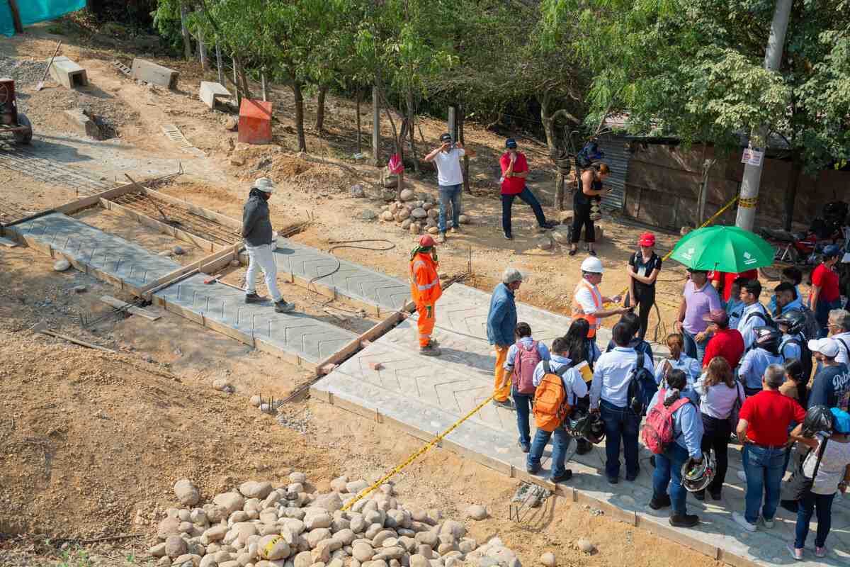 Grupo de personas posando junto a una obra de pavimentación durante la visita técnica.