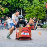 Un equipo participante corre con su carro de balineras mientras sus integrantes lo empujan con entusiasmo en plena competencia de la Semana Universitaria 2024.