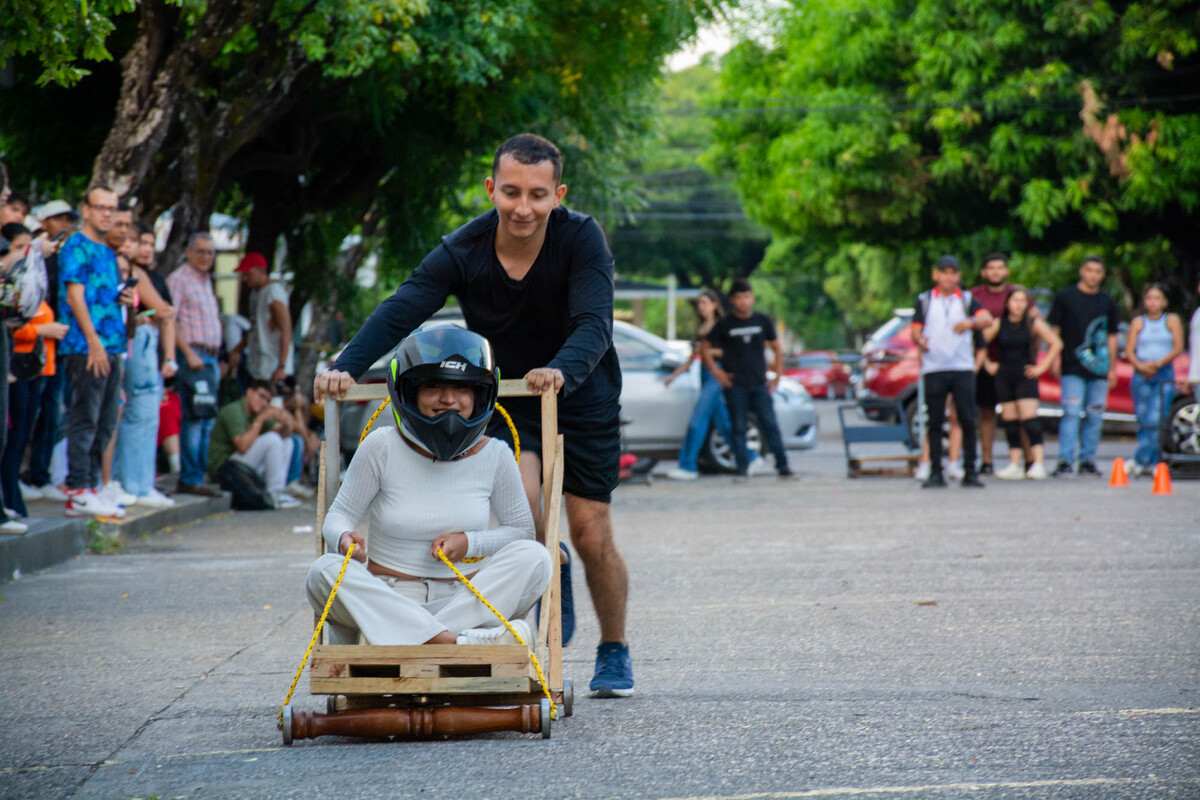 Un equipo participante corre con su carro de balineras mientras sus integrantes lo empujan con entusiasmo en plena competencia de la Semana Universitaria 2024.