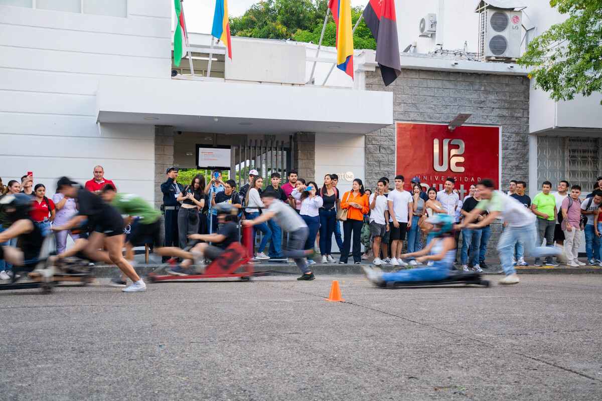 Estudiantes participando en la Carrera de Balineras, mientras corren con sus carros en la pista durante la Semana Universitaria 2024 en la Universidad Piloto de Colombia.