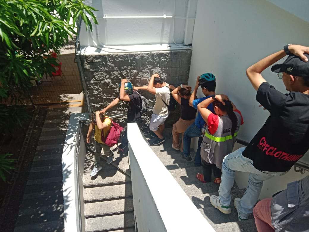 Estudiantes de la Universidad Piloto de Colombia participan en una capacitación para un simulacro de evacuación durante la Semana de la Salud, marchando en fila.