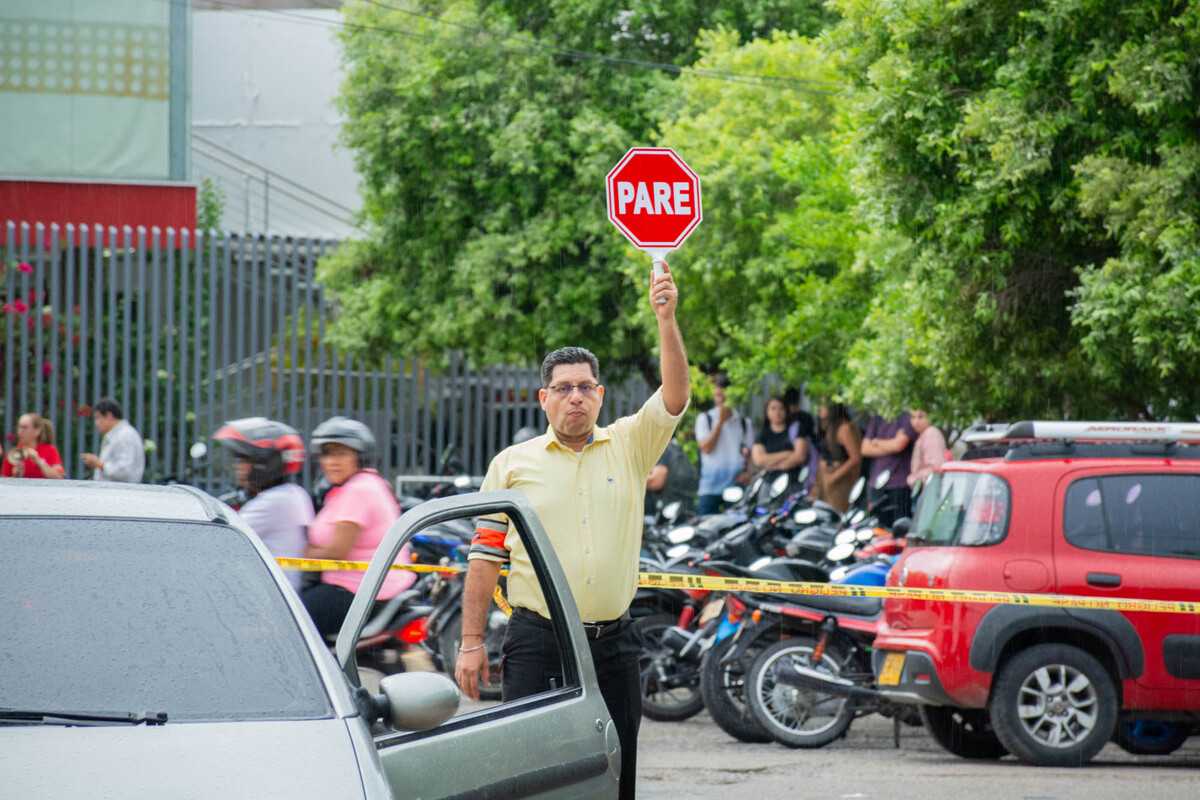 Uno de los brigadistas de la Universidad controlando el tráfico con una señal de Pare/Siga. En la foto él está levantando la señal en alto y se observan vehículos a su alrededor. Durante el Simulacro Nacional de Evacuación por Sismo llevado a cabo en la Universidad Piloto de Colombia, Seccional del Alto Magdalena, en Girardot.