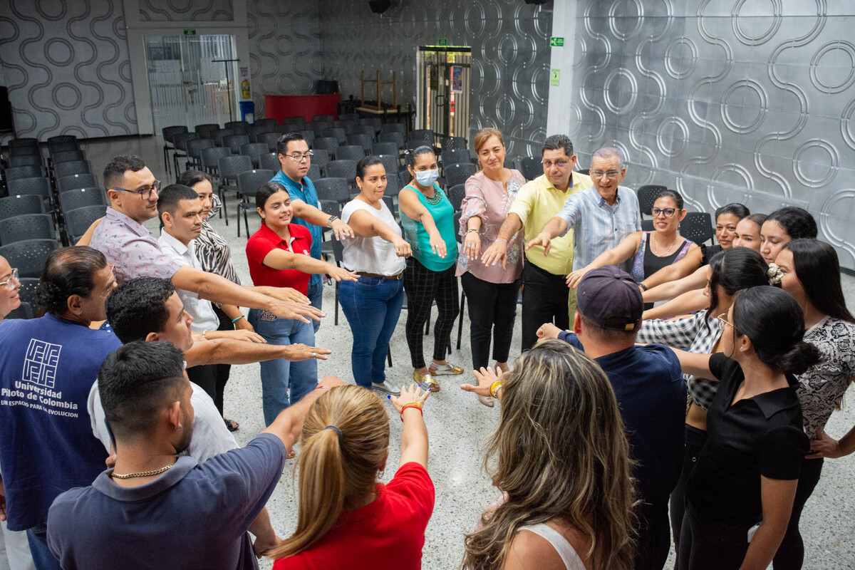 El equipo de Brigadistas de la Universidad Piloto de Colombia, Seccional del Alto Magdalena, durante la fase de preparación antes del Simulacro Nacional de Evacuación por Sismo llevado a cabo en Girardot. Se observa que todos están formando una elipse, mirando hacia el centro y juntando las manos.