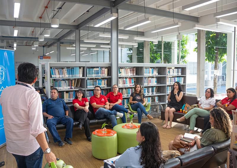 Docentes, directivos y empresarios reunidos en la biblioteca universitaria durante el encuentro Café Empresarial del programa de Administración Logística, enfocado en alianzas estratégicas y beneficios tributarios de la DIAN